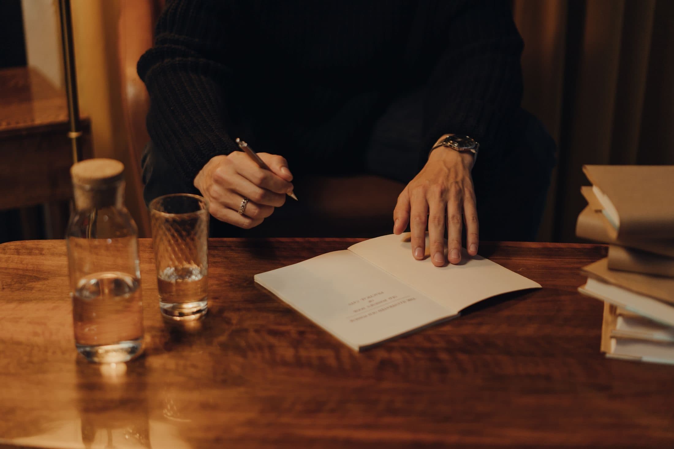 Una persona rilegge il proprio testo a un tavolo, con quaderno e penna